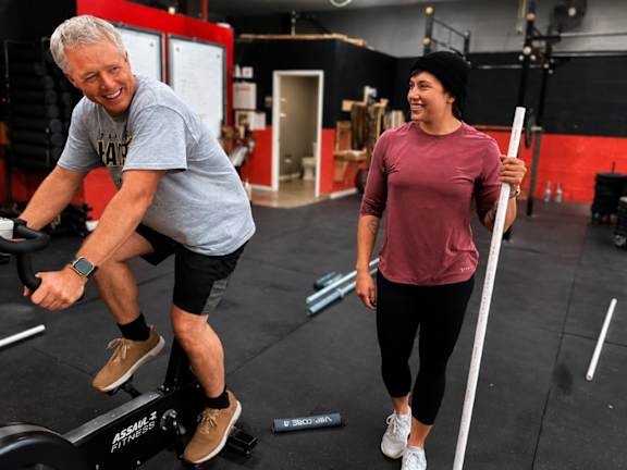 A man and a woman are exercising in a gym.