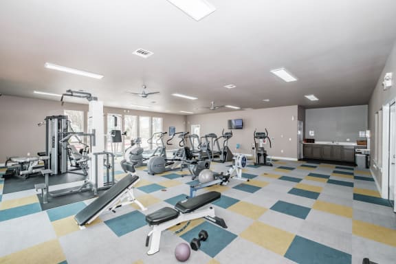 a spacious fitness room with cardio equipment and a flat screen tv