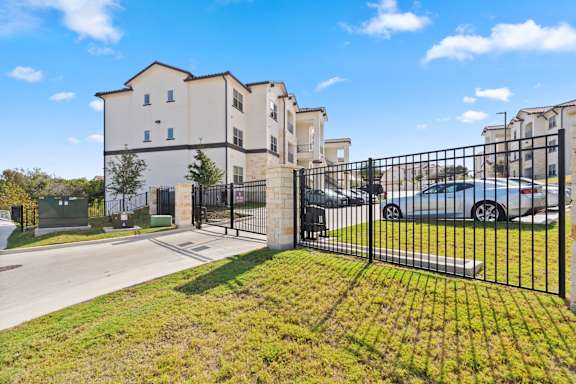 A gated community with a large white building and a black fence.