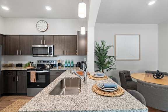 A modern kitchen with a granite countertop and a clock on the wall.