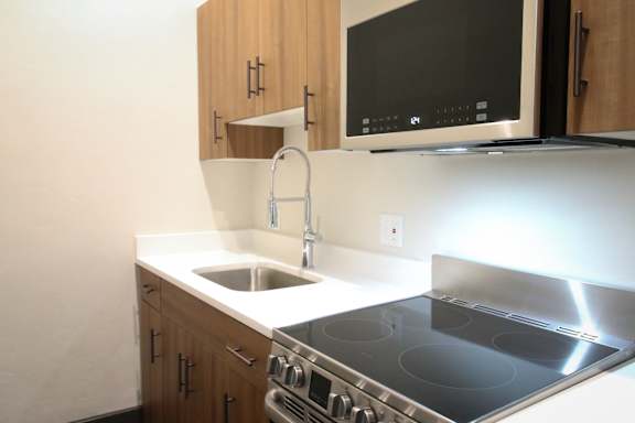 A modern kitchen with a stove, sink, and microwave.