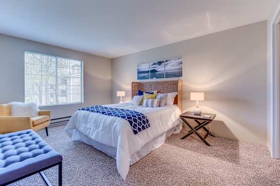 A bedroom with a large bed and a chair.