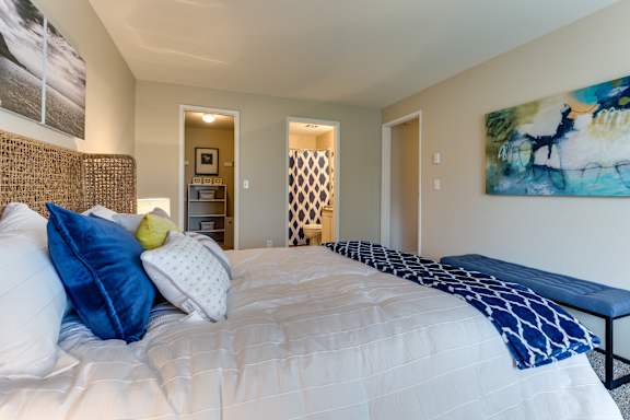 A bedroom with a large bed and a painting on the wall.