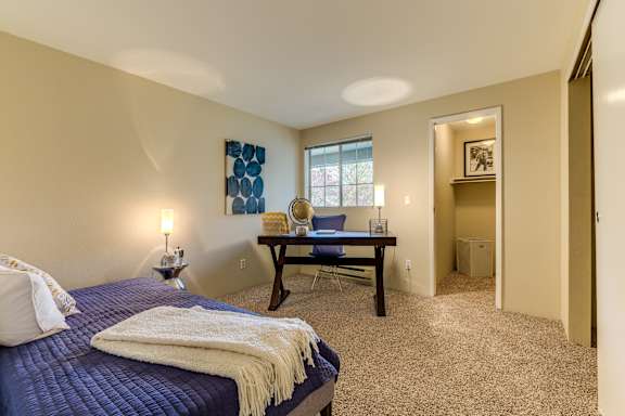 A bedroom with a bed, a desk, and a chair.