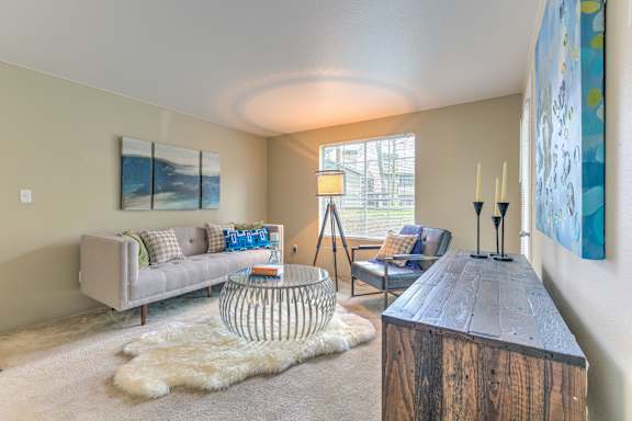 A living room with a grey couch, a wooden coffee table, and a white rug.