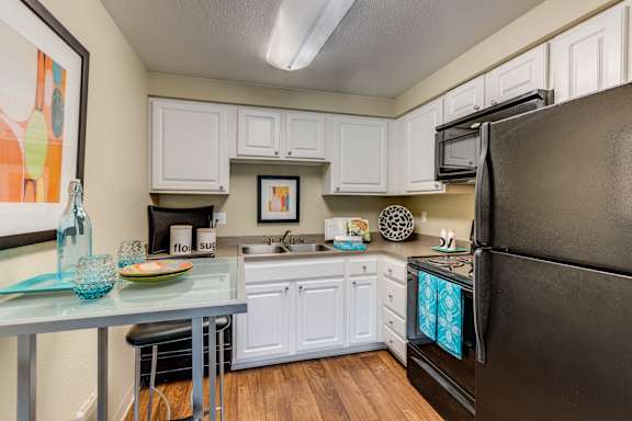 A kitchen with white cabinets and a black refrigerator.