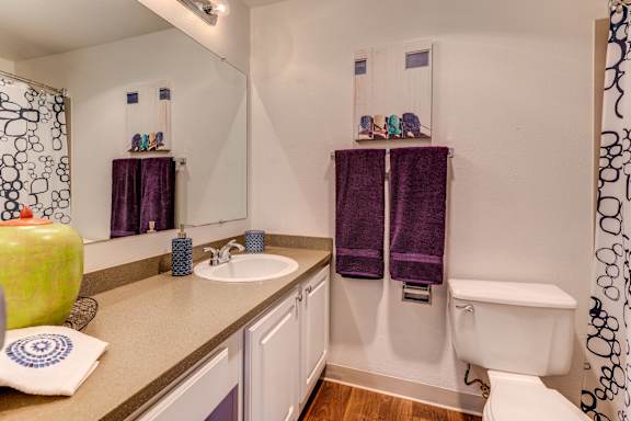 A bathroom with a white tub and purple towels.