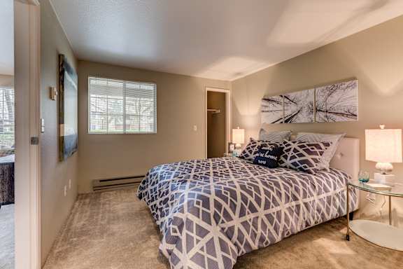 A bedroom with a bed, nightstand, and lamp.