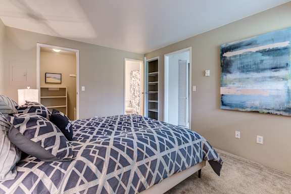 A bedroom with a large bed and a painting on the wall.