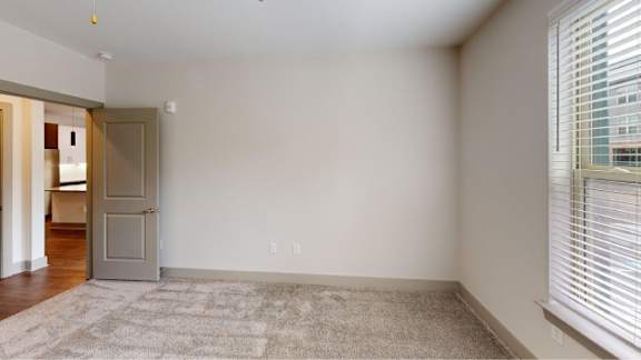 A room with a rug on the floor and a door on the left.