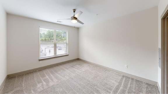 A room with a ceiling fan and a window with blinds.