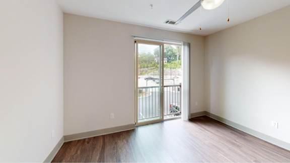 A room with a sliding glass door leading to a balcony.