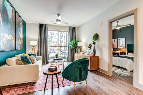 A living room with a white couch, a green chair, and a painting on the wall.