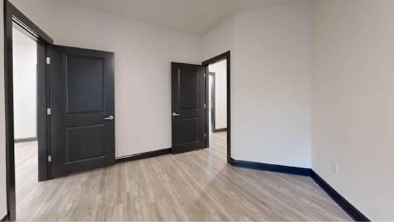 A room with a black door and a wooden floor.