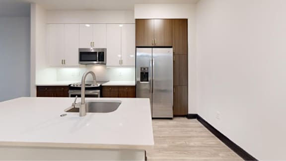 A modern kitchen with a white countertop and stainless steel appliances.