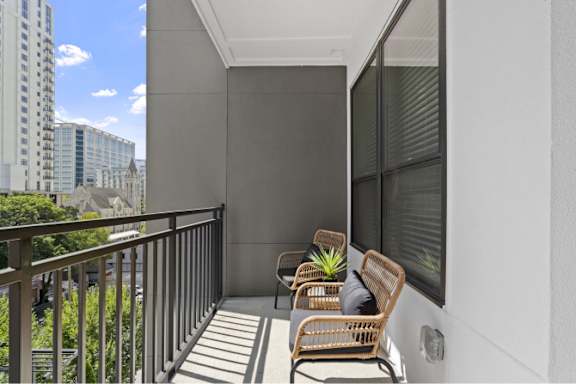 A balcony with two chairs and a table with a plant on it.