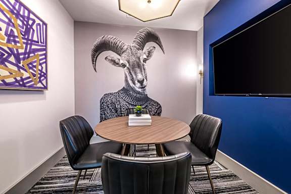 A conference room with a table, chairs, and a painting of a ram on the wall.