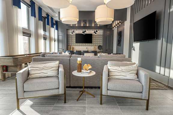 Two grey chairs with white pillows are in front of a grey sofa.