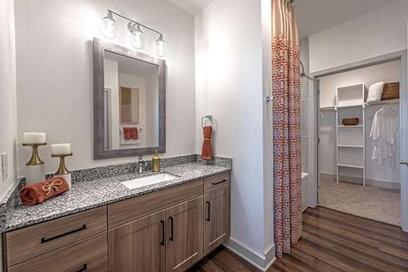 A bathroom with a sink, mirror, and wooden cabinets.