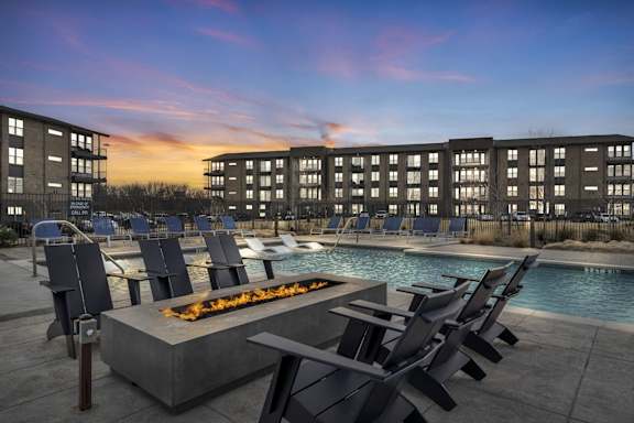 A poolside area with chairs and a fire pit in front of a building.