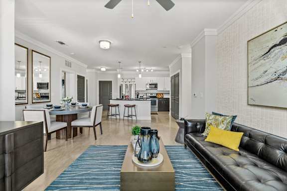 A modern living room with a black leather couch and a dining table set up.