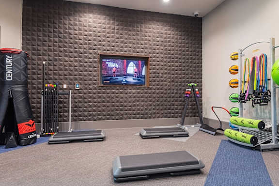 A gym with a television on the wall and various exercise equipment.