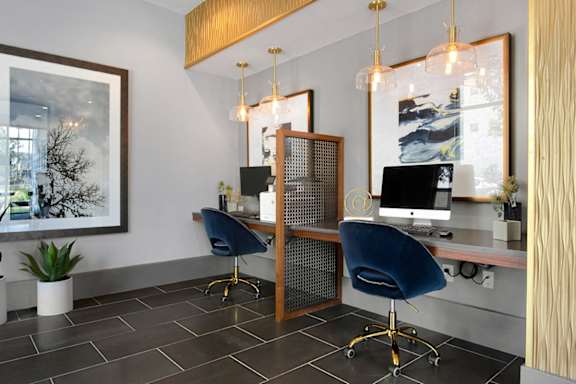 A modern office with a wooden desk and blue chairs.