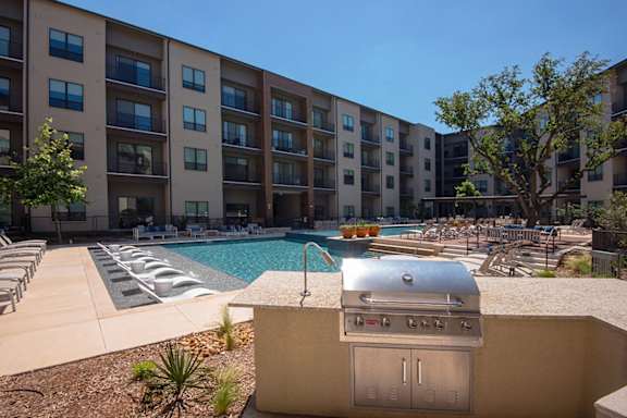 A pool and hot tub area in front of apartment buildings.