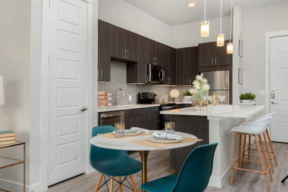 A kitchen with a table set for two and a bar stool.