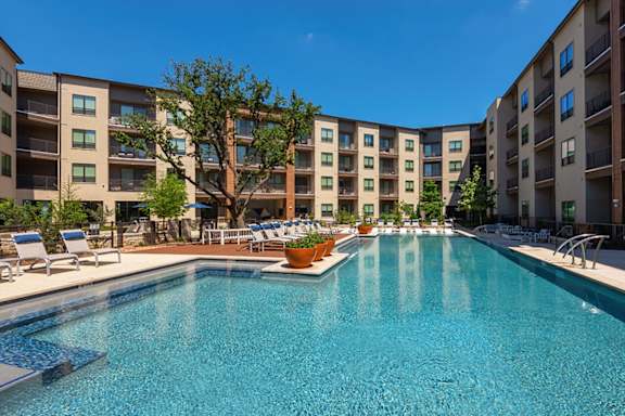 A large swimming pool in front of apartment buildings.