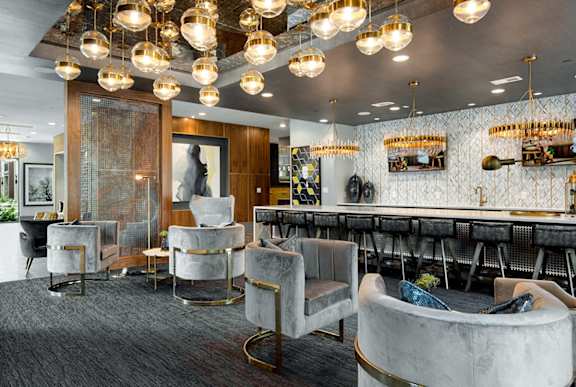 A modern lounge area with grey carpeting and a variety of seating options.