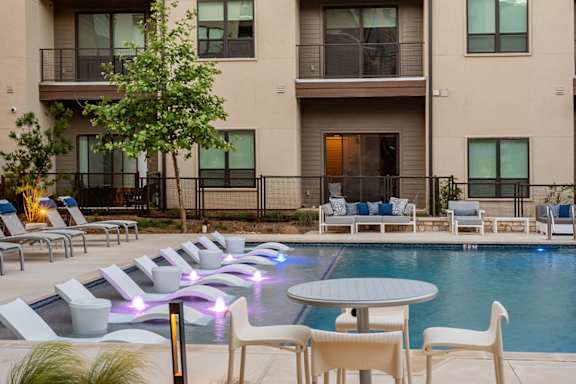 A poolside area with chairs and a table.