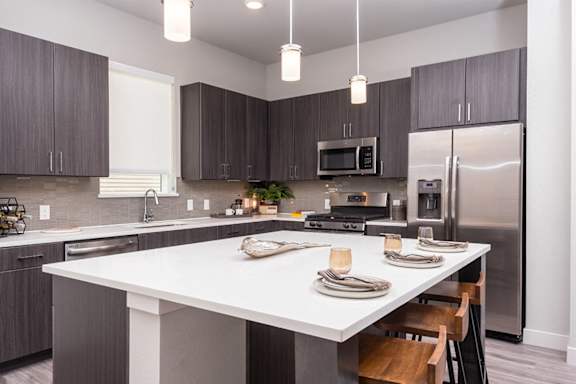 A modern kitchen with a white island and dark brown cabinets.