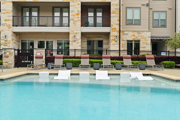 A pool with white chairs and a building in the background.