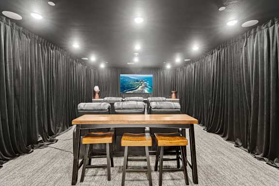 A room with a long table and chairs with a painting on the wall.
