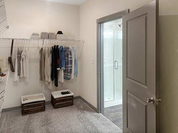 a walk in closet with clothes hanging on a rack and a closet door to a