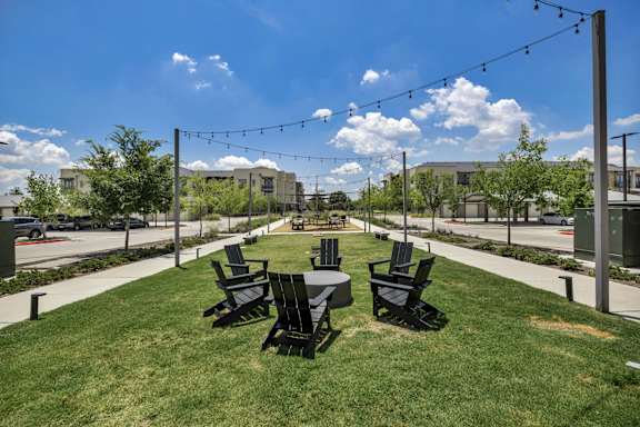 A sunny day at a park with black chairs and tables.