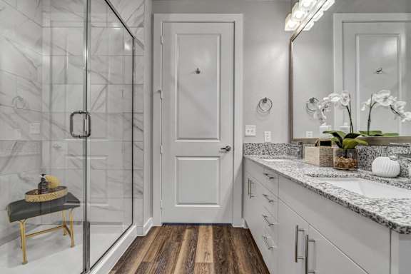 A bathroom with a white door, a mirror, and a sink.