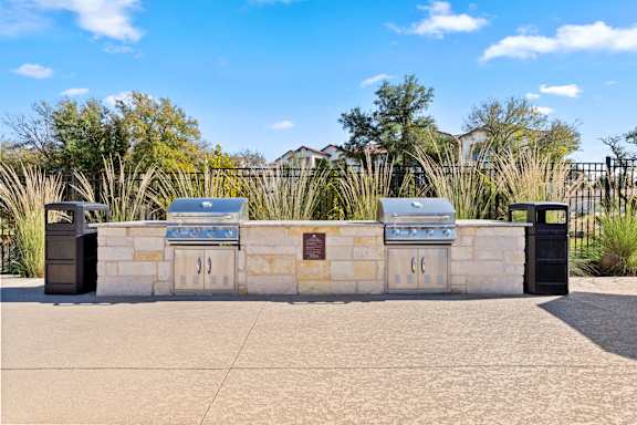 Three grills are lined up on a stone wall.