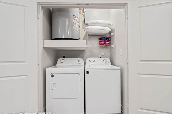 A white laundry room with a washer and dryer in the doorway.