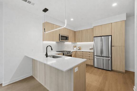 A modern kitchen with a white countertop and wooden cabinets.