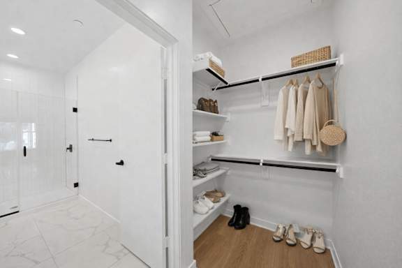 A white closet with a shelf and shoes on the floor.