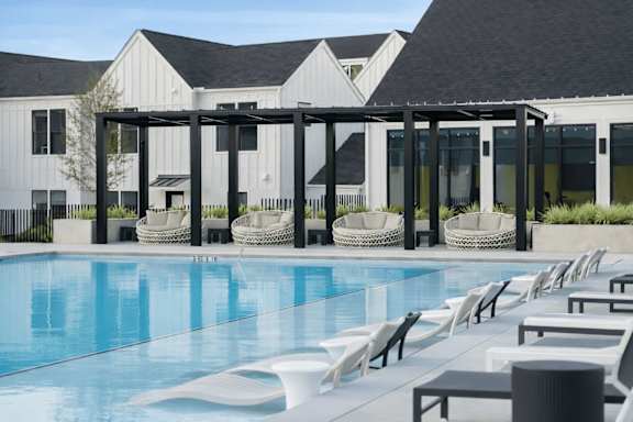 A pool area with chairs and a building in the background.