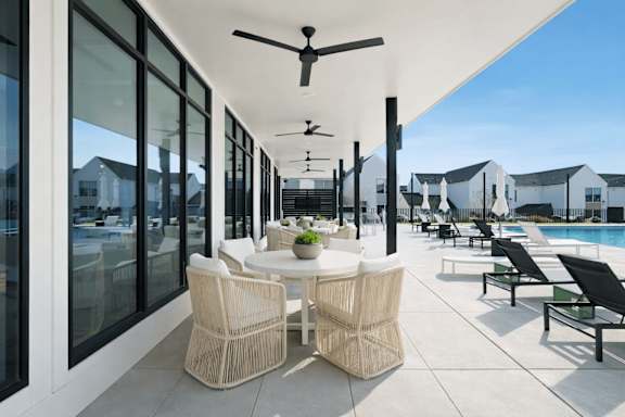 A patio with a table and chairs and a ceiling fan.