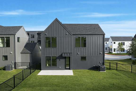 A modern house with a black fence and green lawn.