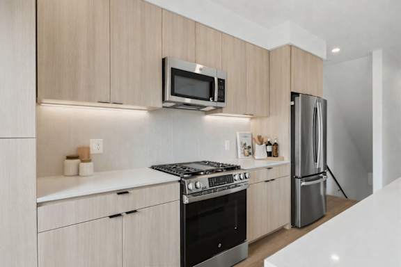 A modern kitchen with a stove, microwave, and refrigerator.