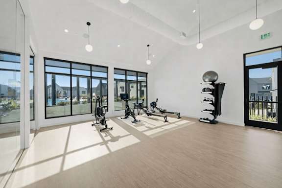 A gym with exercise equipment and a view of the outside.