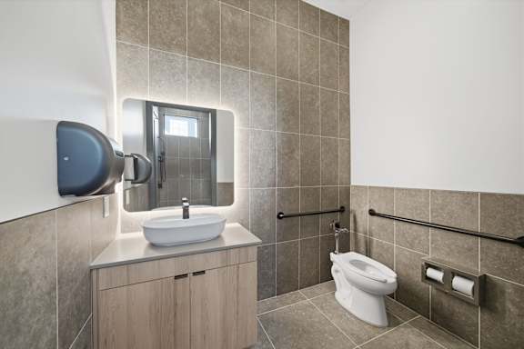 A bathroom with a white toilet and a sink with a mirror above it.