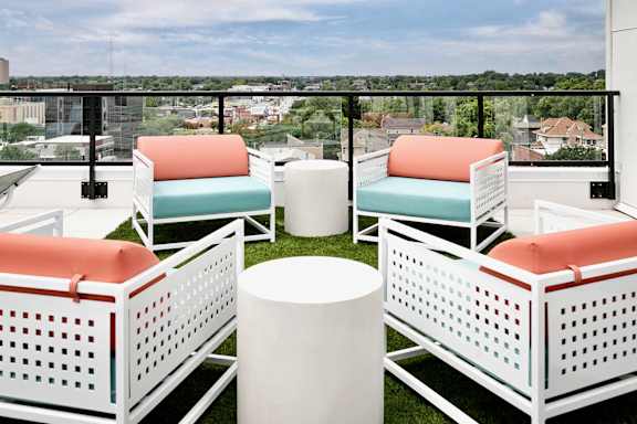 A white chair with orange cushion is placed on the balcony.