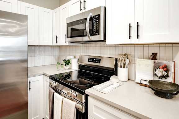 A kitchen with white cabinets and a black stove top.